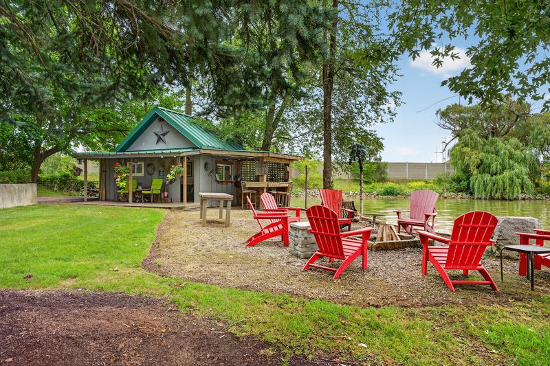 Muskoka chairs around the fire pit by the bunkie