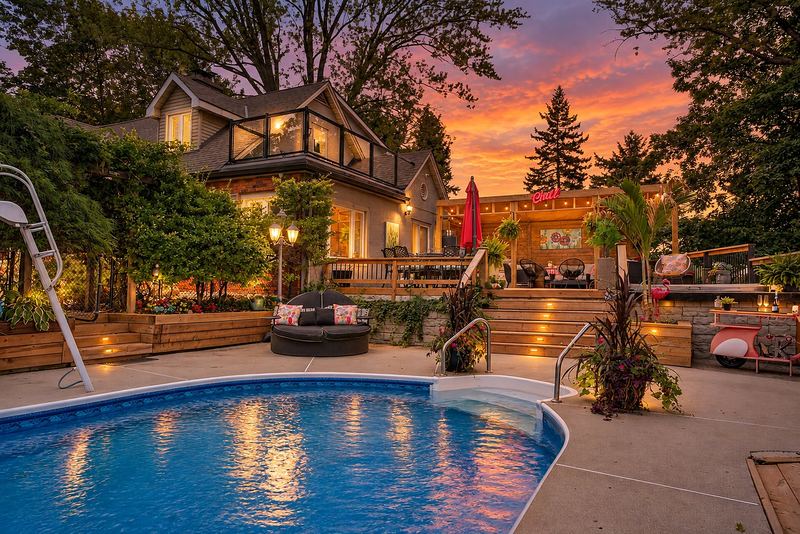 The pool, the deck steps and the house glowing at dusk (virtual twilight)